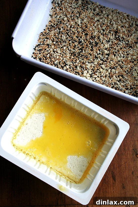 Golden Sesame Tofu with Tangy Nuoc Cham Drizzle 11 Two trays: one with beaten egg and another with sesame seeds and panko bread crumbs, set for dredging.