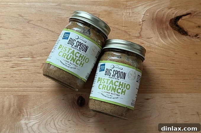 Two jars of Big Spoon Pistachio Crunch almond butter, showcasing its appealing texture and gourmet packaging.