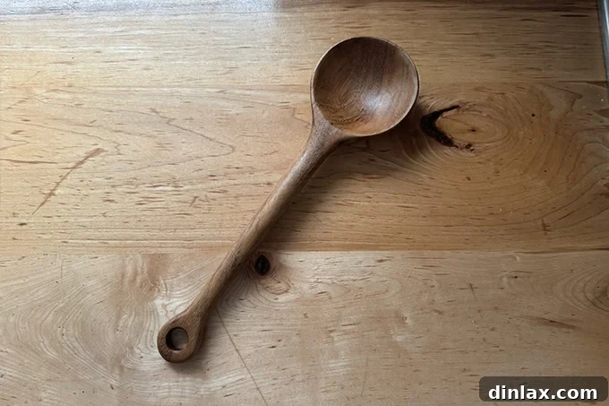 A hand-carved Guatemalan wooden bean spoon, rustic and functional, suggesting traditional culinary craftsmanship.