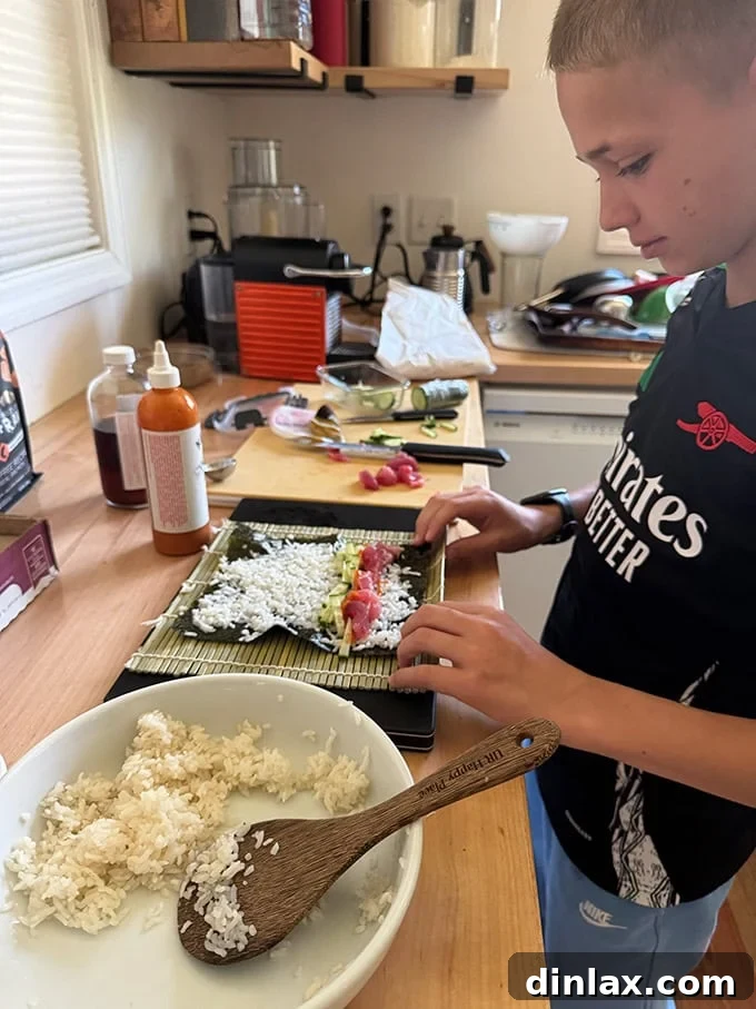 A young person, Graham, intently focused on making sushi, demonstrating the hands-on and engaging nature of the sushi kit gift.