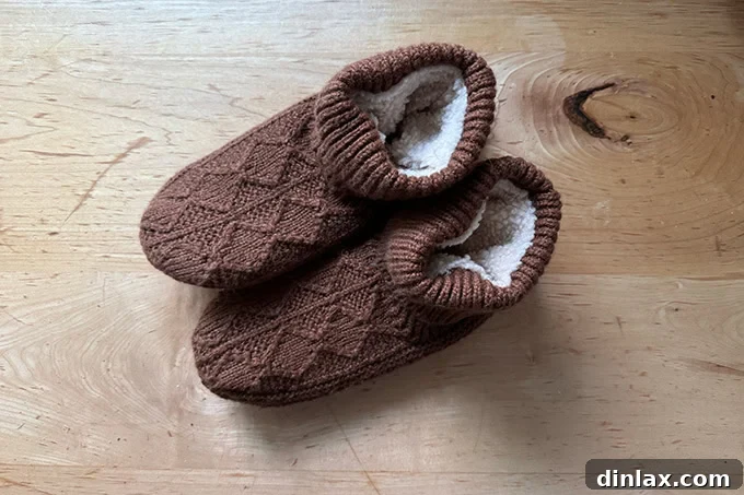 A pair of soft, sherpa-lined Bombas slipper booties in a neutral tone, casually placed to emphasize their inviting texture and comfort.