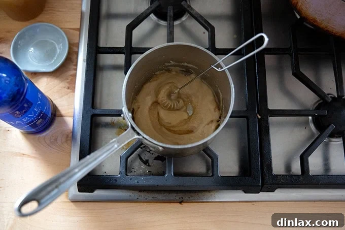 A small saucepan with a cooked roux, to which a measure of Sherry has just been added, creating a thick, aromatic mixture.