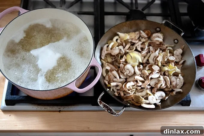 A large pot of boiling pasta on a stovetop next to a sauté pan filled with sliced mushrooms, beginning to brown.