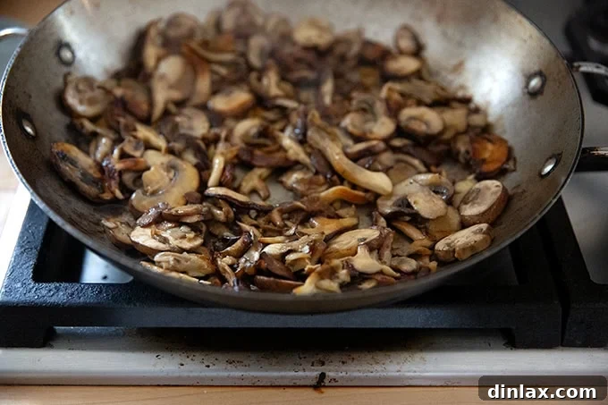 A close-up view of a large pan of sautéed mushrooms, showcasing their rich brown color and tender texture, ready for the tetrazzini.