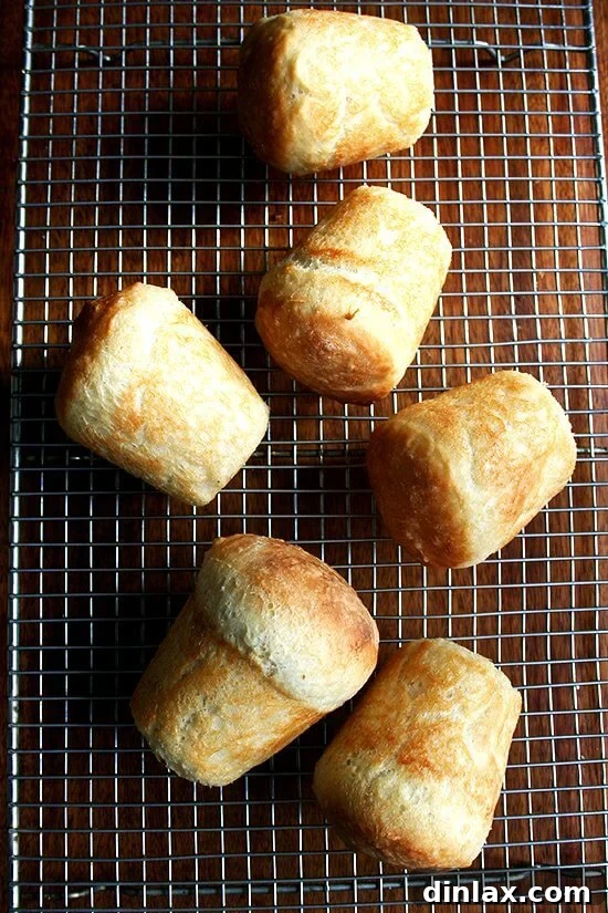 Paul Steindler's Cabbage Soup and Peasant Bread: A Hearty Duo 12 A rustic wooden cutting board featuring a large, artisan loaf of peasant bread alongside several smaller mini loaves, showcasing the versatility of the recipe.