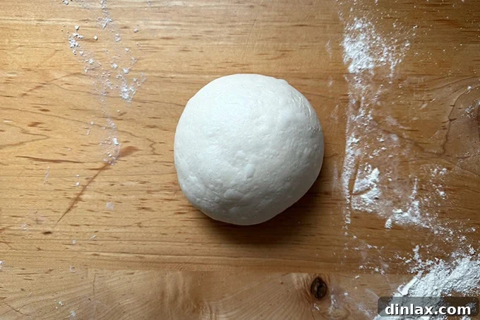 Giant sandwich roll dough, balled up on a countertop.