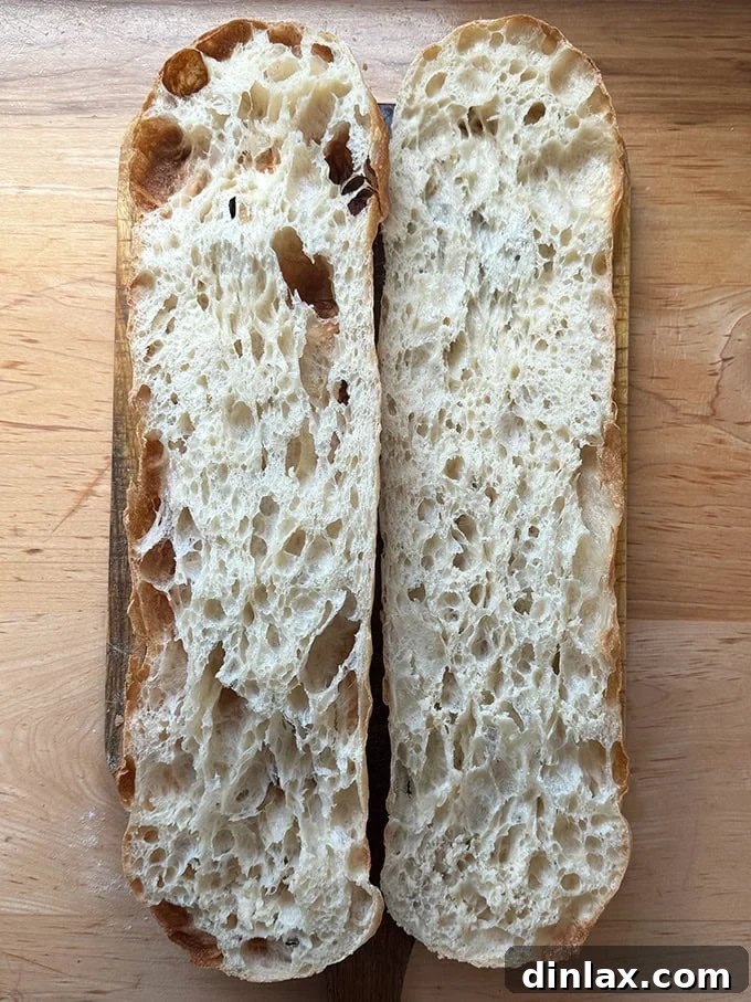 Giant sandwich roll dough, halved on a cutting board.