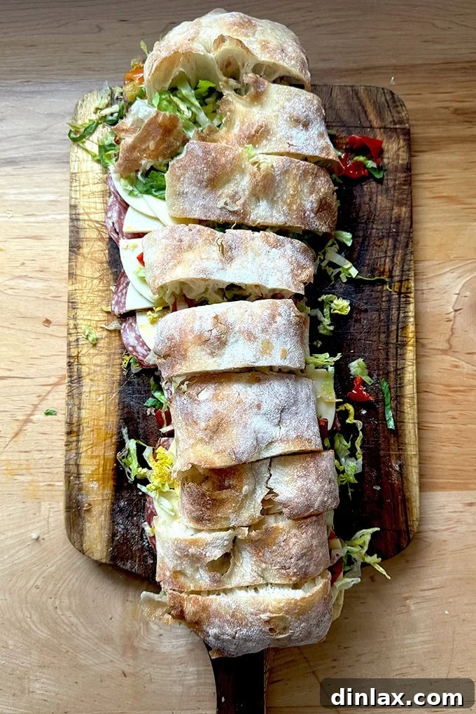 A giant sandwich on a cutting board, filled with an Italian combo.
