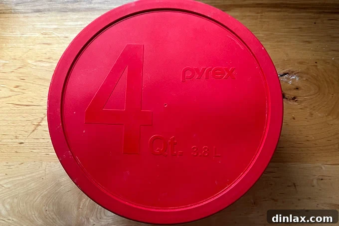 A lidded 4-qt Pyrex bowl holding sandwich roll dough.