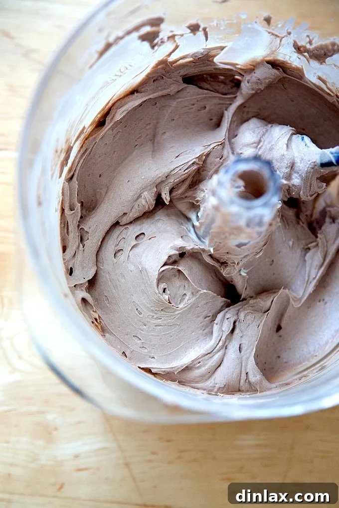 A stand mixer holding chocolate whipped cream cheese frosting, showcasing its smooth and creamy texture.