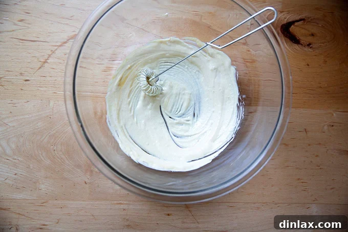 A mayonnaise-mustard mixture stirred together in a large bowl.