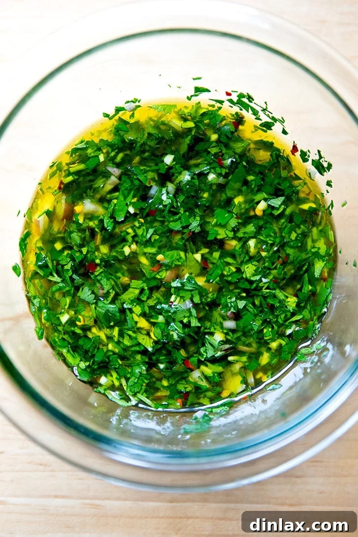 Zesty Homemade Chimichurri 2 A bowl of stirred together chimichurri, showcasing its vibrant green color and fresh texture.