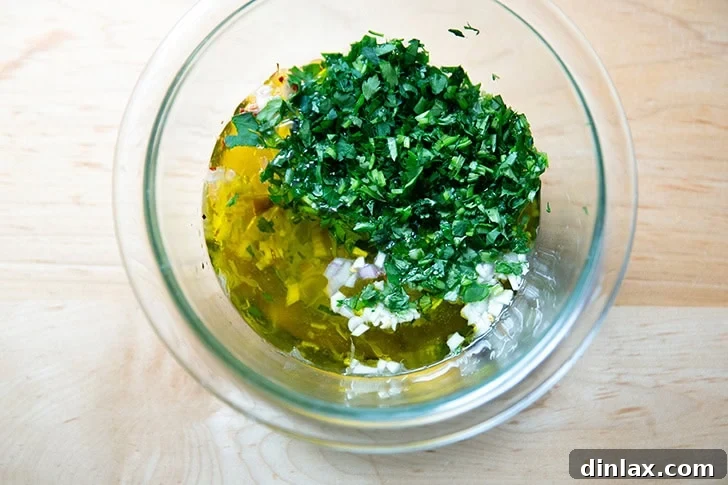 Zesty Homemade Chimichurri 5 Freshly chopped parsley and cilantro added to the bowl containing the macerated shallots, garlic, and vinegar mixture, followed by a pour of olive oil.