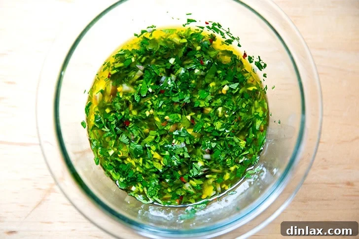 Zesty Homemade Chimichurri 6 A close-up of the chimichurri mixture being stirred thoroughly in a bowl, showing the vibrant green and textural elements.