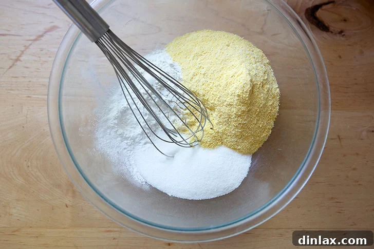 The dry ingredients to make cornbread in a large bowl with a whisk in it.