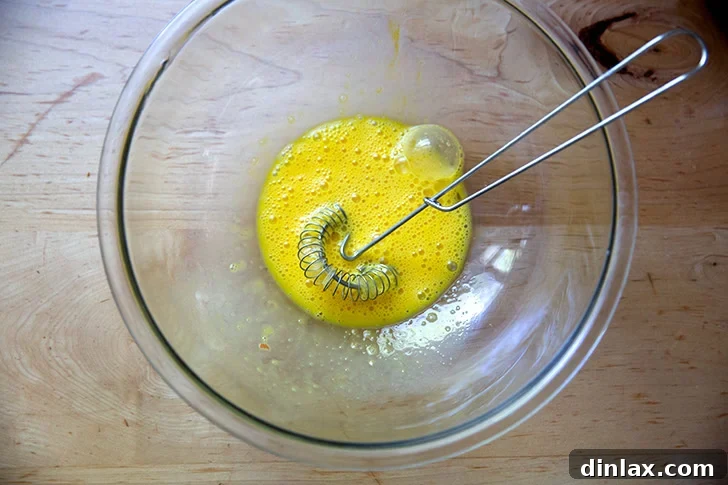 Two eggs beaten together in a large bowl.
