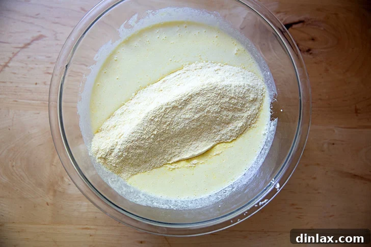 The dry ingredients to make cornbread added to the wet ingredients in a large bowl.